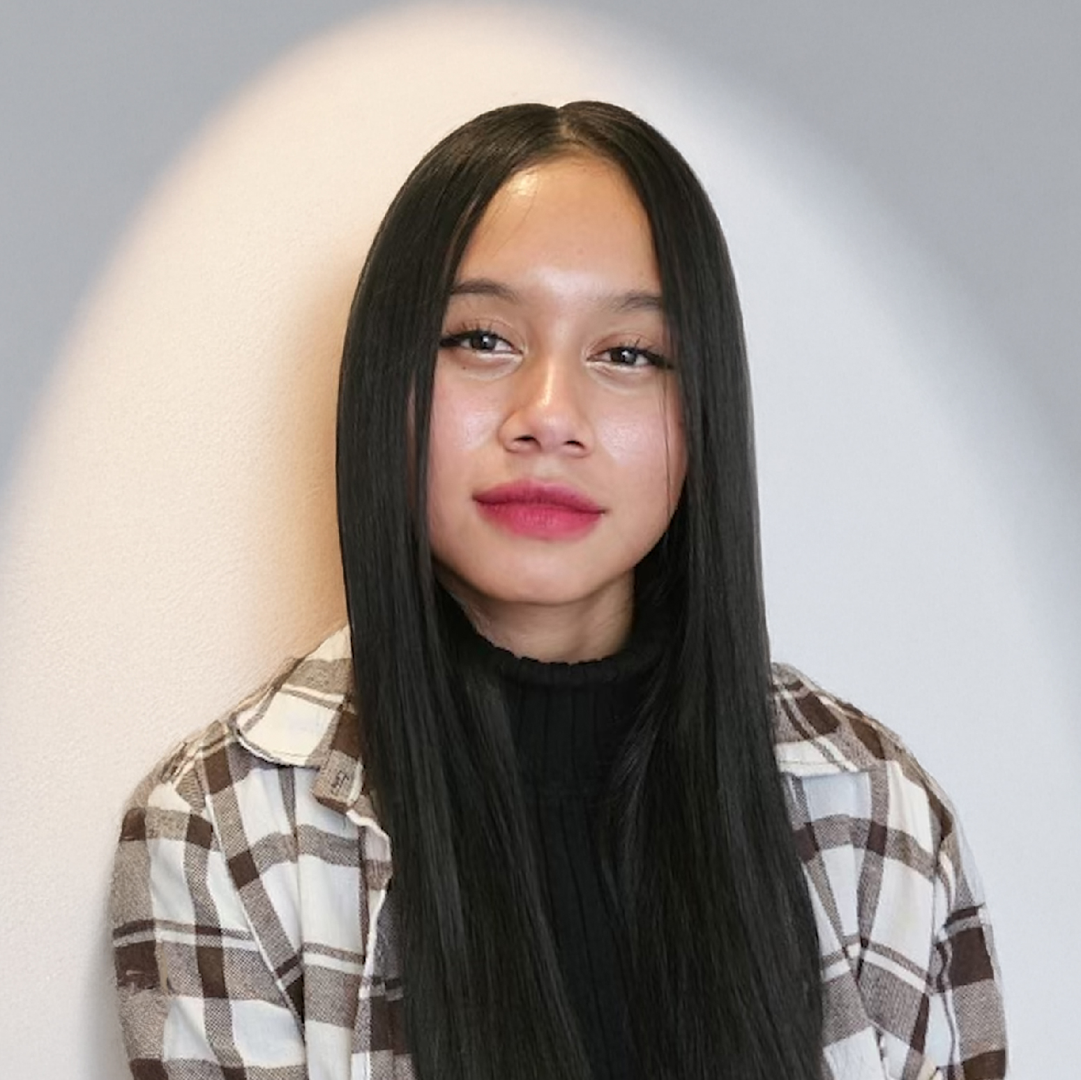 TLA Project Connect student Greyshel, a young woman with long dark hair, wearing a brown and white flannel shirt with a black t-shirt.